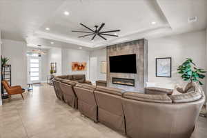 Living room with a tile fireplace, a raised ceiling, visible vents, and recessed lighting