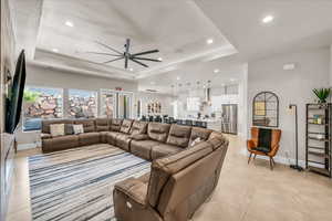 Living area with baseboards, a raised ceiling, a ceiling fan, and recessed lighting