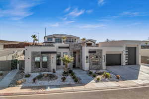 Contemporary house featuring an attached garage, stone siding, concrete driveway, and stucco siding