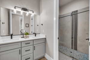 Bathroom with baseboards, double vanity, a sink, and a shower stall