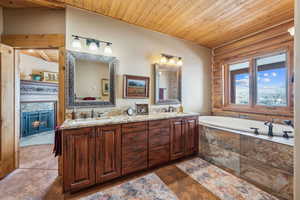 Full bath with wooden ceiling, a sink, a bath, double vanity, and rustic walls