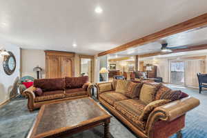 Carpeted living room with a textured ceiling, baseboards, beam ceiling, and recessed lighting