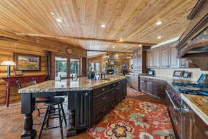 Kitchen featuring dark brown cabinets, range with two ovens, an island with sink, and recessed lighting