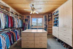 Walk in closet with ceiling fan and dark colored carpet