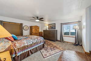 Carpeted bedroom featuring ceiling fan and baseboards