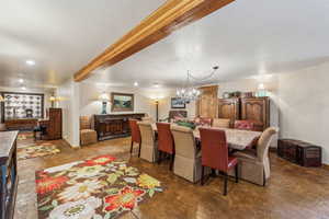 Dining space featuring a textured ceiling, concrete floors, baseboards, beam ceiling, and an inviting chandelier