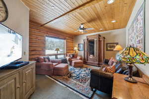 Living area with dark colored carpet, recessed lighting, wood ceiling, and a ceiling fan