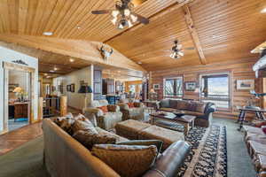 Living area with ceiling fan, high vaulted ceiling, carpet floors, wood ceiling, and beam ceiling