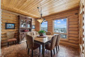 Dining room with rustic walls, wooden ceiling, and dark wood finished floors