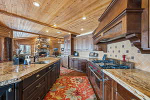 Kitchen featuring tasteful backsplash, recessed lighting, a sink, dark brown cabinets, and double oven range