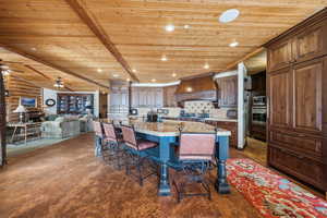 Kitchen featuring stainless steel appliances, premium range hood, a kitchen island, open floor plan, and a kitchen bar