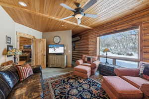 Carpeted living room with wood ceiling, log walls, ceiling fan, and recessed lighting