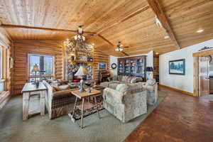 Living room featuring vaulted ceiling with beams, rustic walls, wooden ceiling, and baseboards