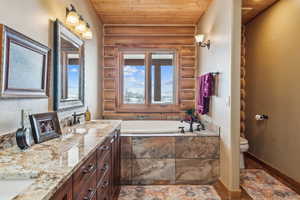 Full bath with a garden tub, log walls, double vanity, wood ceiling, and a sink