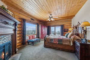 Carpeted bedroom with wood ceiling, access to exterior, a fireplace with flush hearth, and ceiling fan