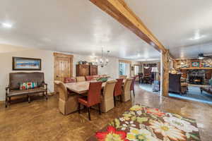 Dining space featuring concrete flooring, beamed ceiling, a fireplace, and a textured ceiling