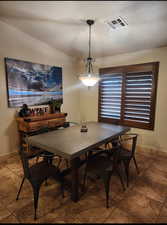 Dining area featuring vaulted ceiling, visible vents, and baseboards