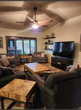 Living room with visible vents, vaulted ceiling, and ceiling fan