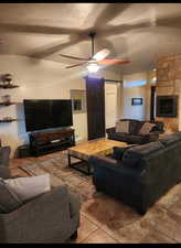 Tiled living area featuring a barn door, a tiled fireplace, ceiling fan, and a textured ceiling