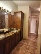 Full bath with double vanity, tile patterned flooring, a sink, and a notable chandelier