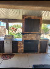 View of patio featuring exterior kitchen, grilling area, and a glass covered fireplace