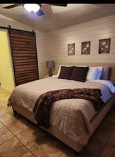 Bedroom featuring tile patterned floors, ceiling fan, and a barn door