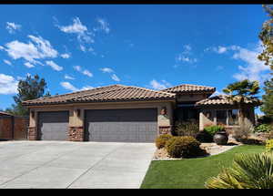 Mediterranean / spanish-style home featuring an attached garage, a tile roof, stone siding, concrete driveway, and stucco siding