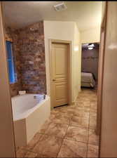 Bathroom featuring visible vents, a bathing tub, a textured ceiling, ensuite bath, and tile patterned flooring