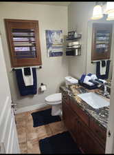 Bathroom with baseboards, vanity, toilet, and tile patterned floors