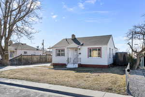 Bungalow-style house with a chimney, fence, a front lawn, and roof with shingles