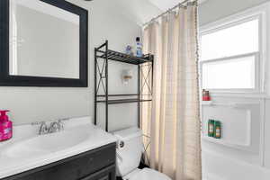 Full bath with toilet, shower / tub combo with curtain, and vanity