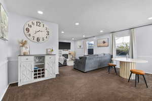 Living room featuring dark colored carpet, a glass covered fireplace, baseboards, and recessed lighting