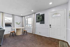 Foyer with recessed lighting, dark carpet, and a textured ceiling