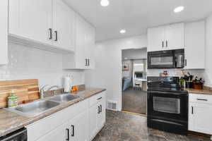 Kitchen with white cabinetry, a sink, visible vents, and black appliances