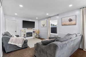 Living room featuring a glass covered fireplace, dark carpet, and recessed lighting