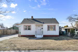 Bungalow-style home featuring a shingled roof, a chimney, a front lawn, and fence