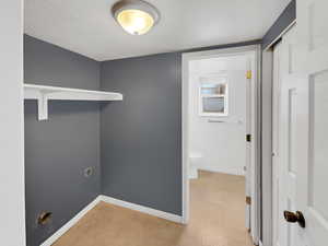 Washroom featuring laundry area, a textured ceiling, baseboards, and hookup for an electric dryer