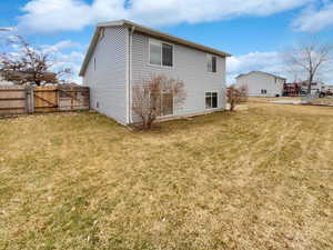 Rear view of property featuring a gate, a yard, and fence