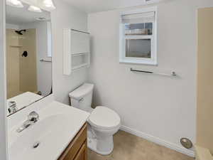 Bathroom featuring toilet, baseboards, visible vents, and vanity