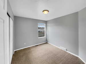 Unfurnished bedroom featuring baseboards, a closet, visible vents, and carpet flooring