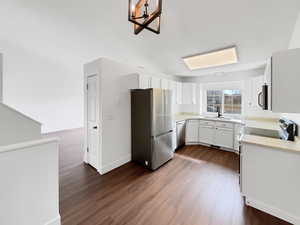 Kitchen with stainless steel appliances, dark wood-style flooring, a sink, and light countertops