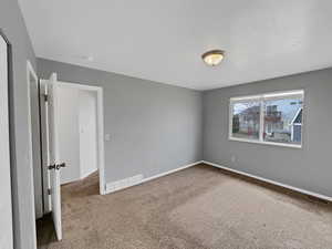 Unfurnished bedroom with carpet floors, visible vents, and baseboards