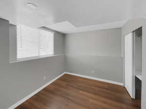 Spare room featuring a textured ceiling, baseboards, and wood finished floors