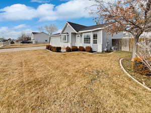 Ranch-style house featuring an attached garage, fence, a front lawn, and roof with shingles