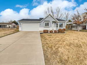 Ranch-style house featuring driveway, an attached garage, fence, and a front yard