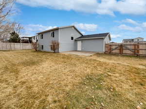 Back of house featuring a fenced backyard, a gate, a lawn, and a patio