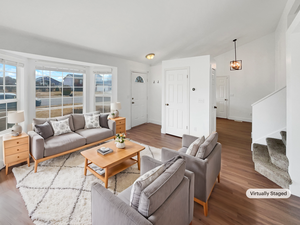 Living area featuring baseboards, stairway, vaulted ceiling, and wood finished floors