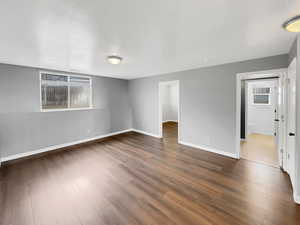 Spare room featuring dark wood-style floors and baseboards