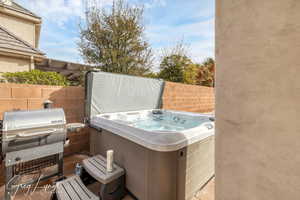 View of patio featuring fence, a grill, and a hot tub