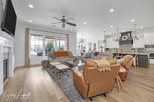 Living area with visible vents, a glass covered fireplace, ceiling fan, light wood-type flooring, and recessed lighting